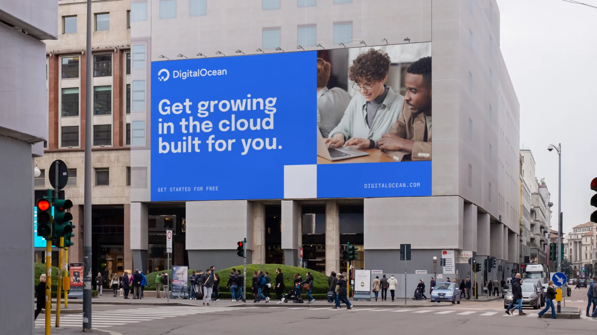 A DigitalOcean billboard on a city street reading 'Get growing in the cloud built for you,' above a photo of two colleagues working together on a laptop.