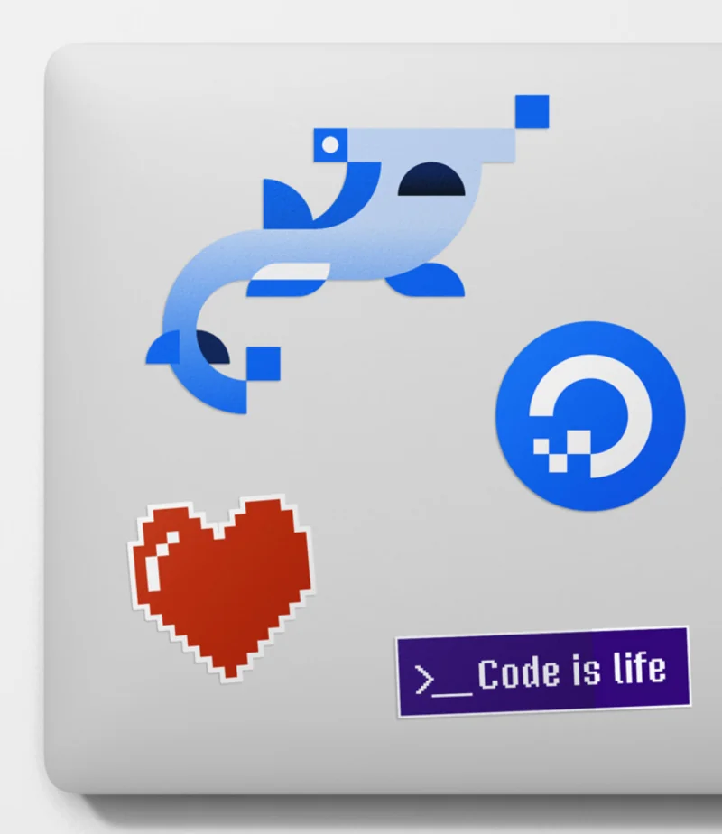 DigitalOcean brand marks and stickers on a laptop lid — the dolphin mark, the logo, a pixel heart, and a 'Code is life' badge.