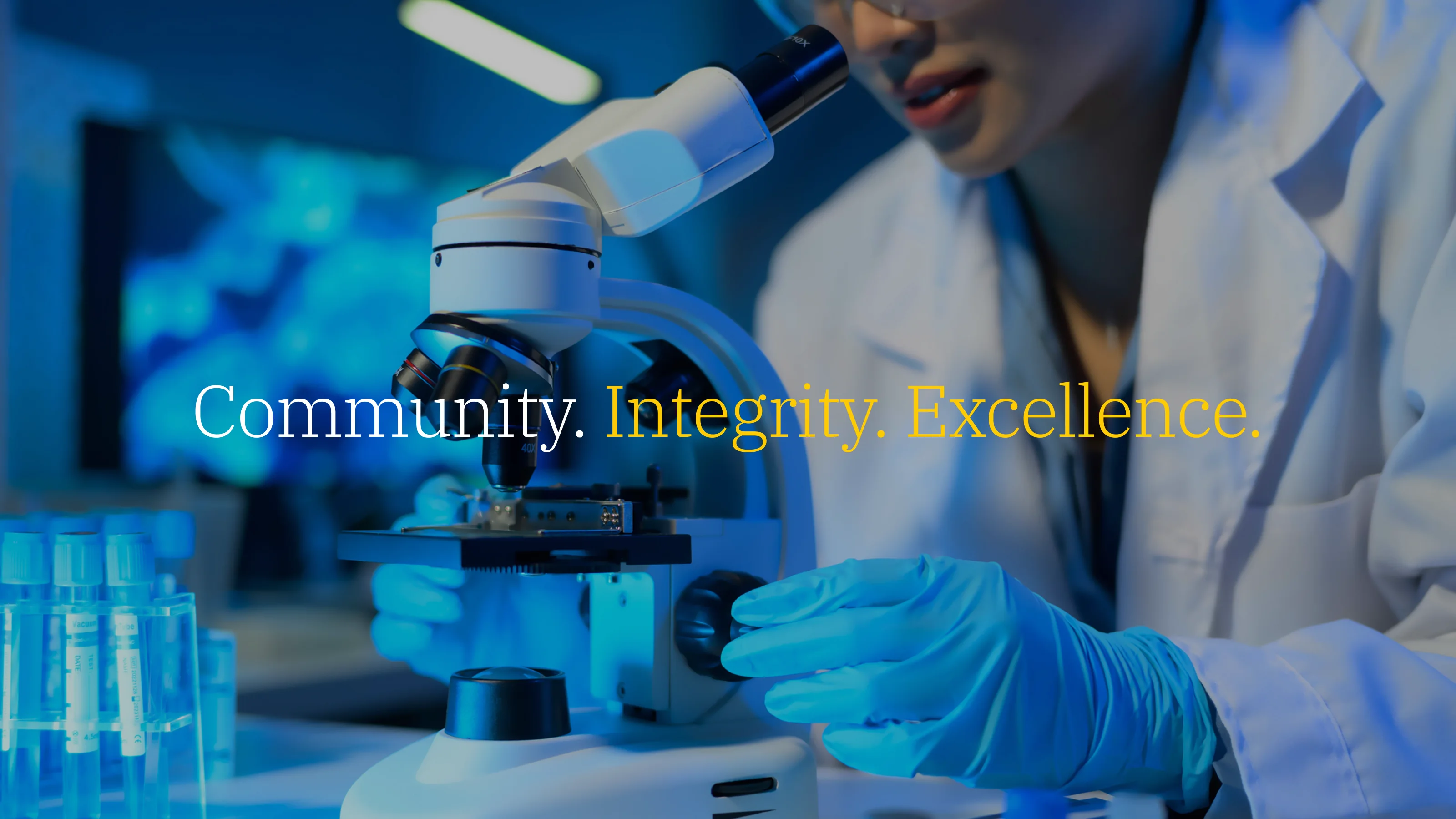 College of Pharmacy hero key visual: a researcher at a microscope in blue lab light, with the tagline 'Community. Integrity. Excellence.' in the maize-and-blue brand.